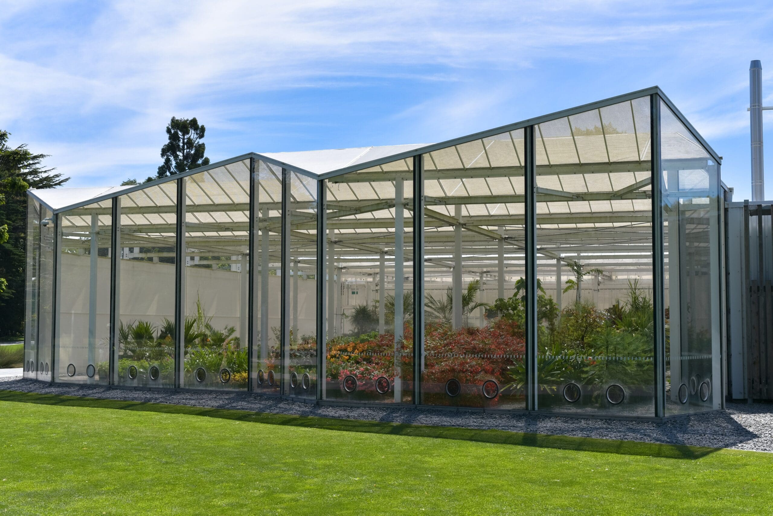 A large outdoor enclosure surrounded by vibrant green grass, showcasing custom screen enclosures Jacksonville FL.