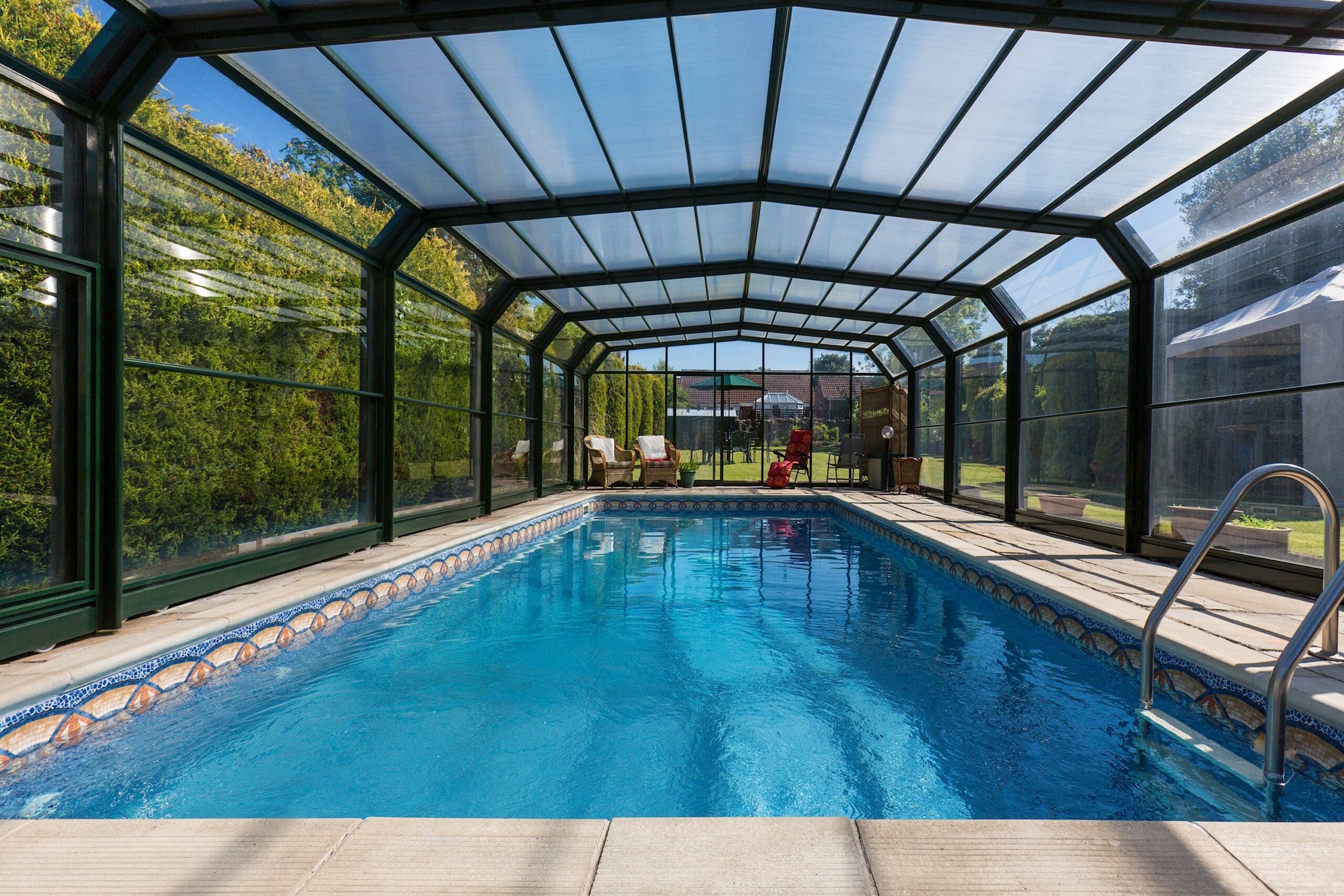 custom screen enclosures installation Jacksonville FL - A large swimming pool surrounded by a lush garden in a country proper