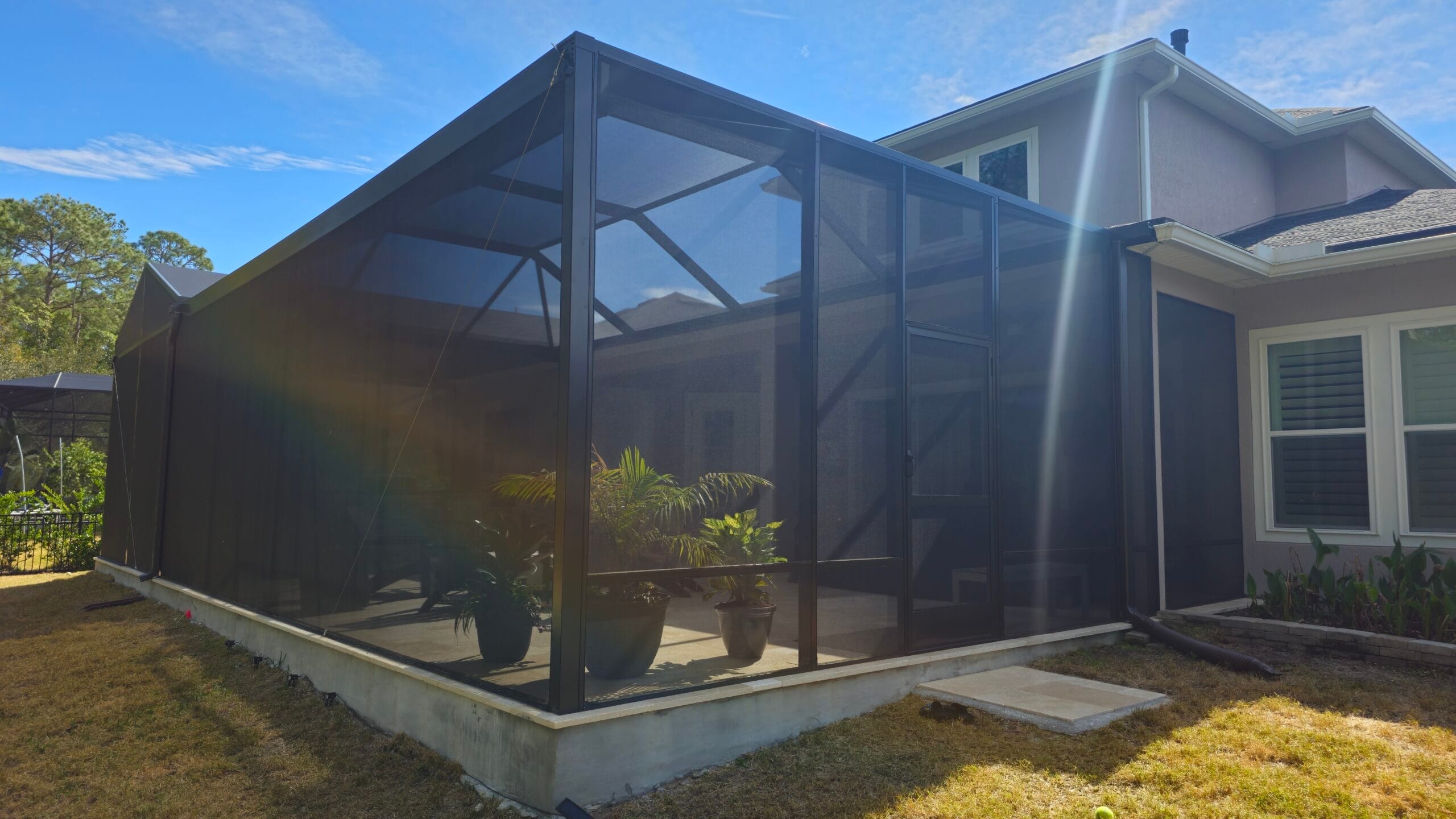 Custom screen enclosures Jacksonville showcasing a modern patio with sleek, white frames and clear panels under a sunny sky.
